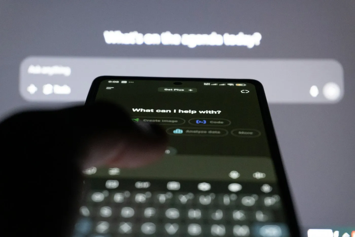Finger hovering over a smartphone showing an AI chatbot screen in a dim room