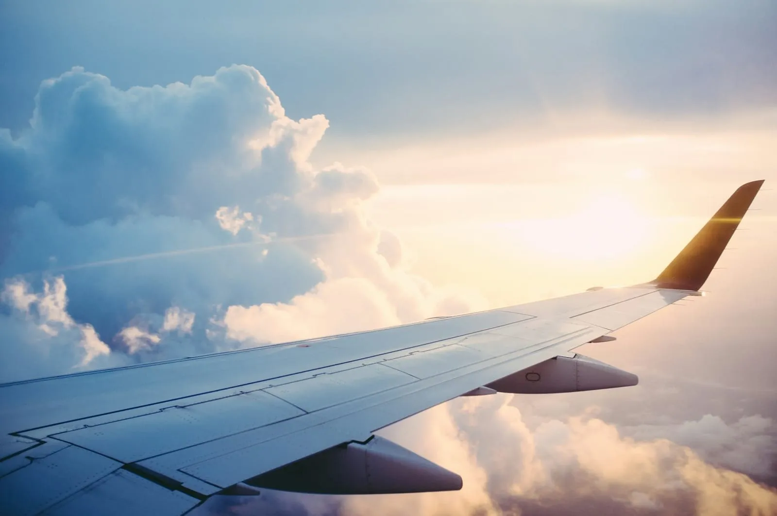 View through an airplane window of the wing above sunlit clouds