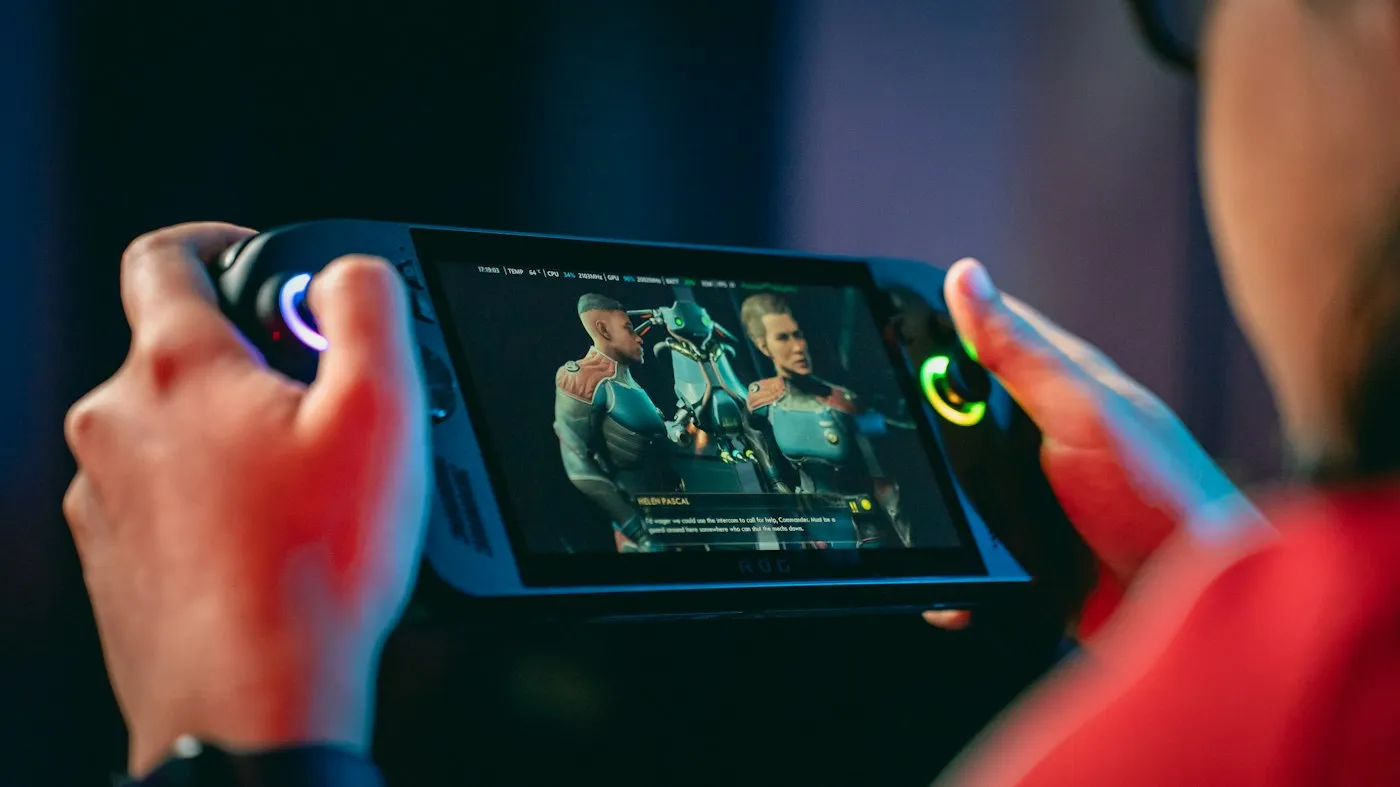 Hands grip a handheld gaming PC with glowing thumbsticks in a dark room