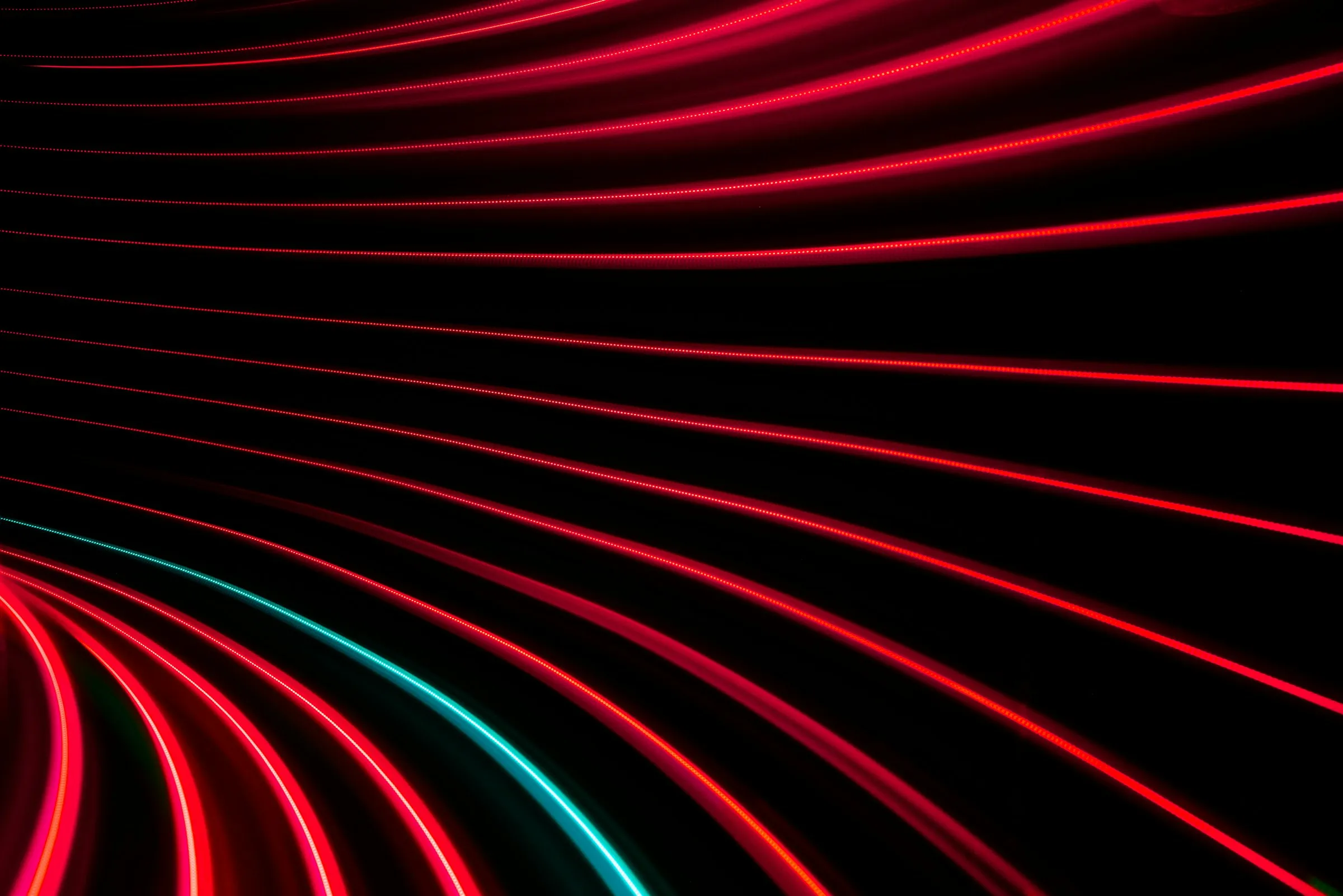 Long-exposure red light trails sweeping across a black background
