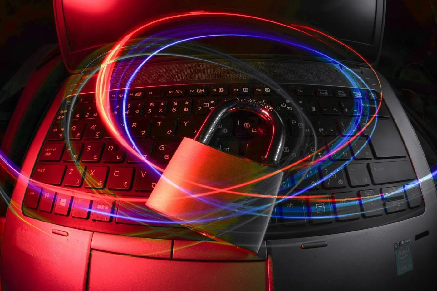 Metal padlock on a laptop keyboard circled by red and blue light trails
