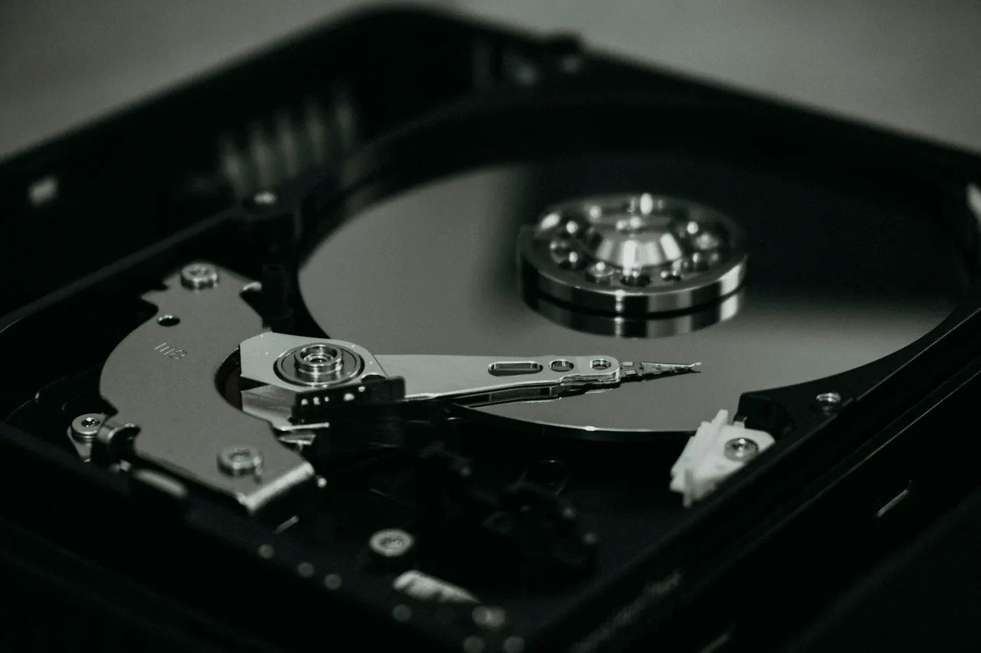 Black-and-white close-up of an opened hard disk drive showing its platter and read-write arm