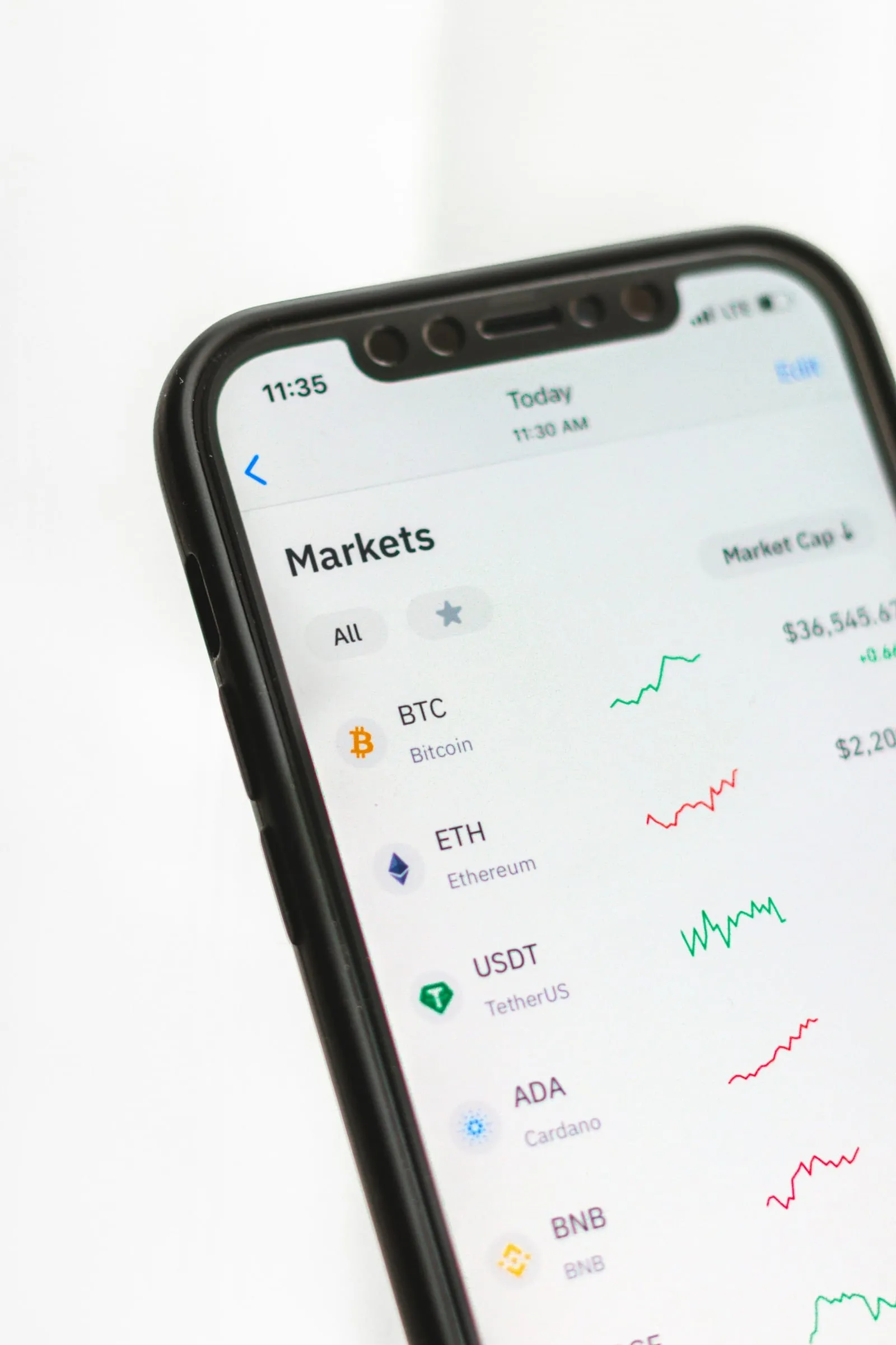 A smartphone displaying a crypto markets app that lists prices for BTC, ETH and USDT