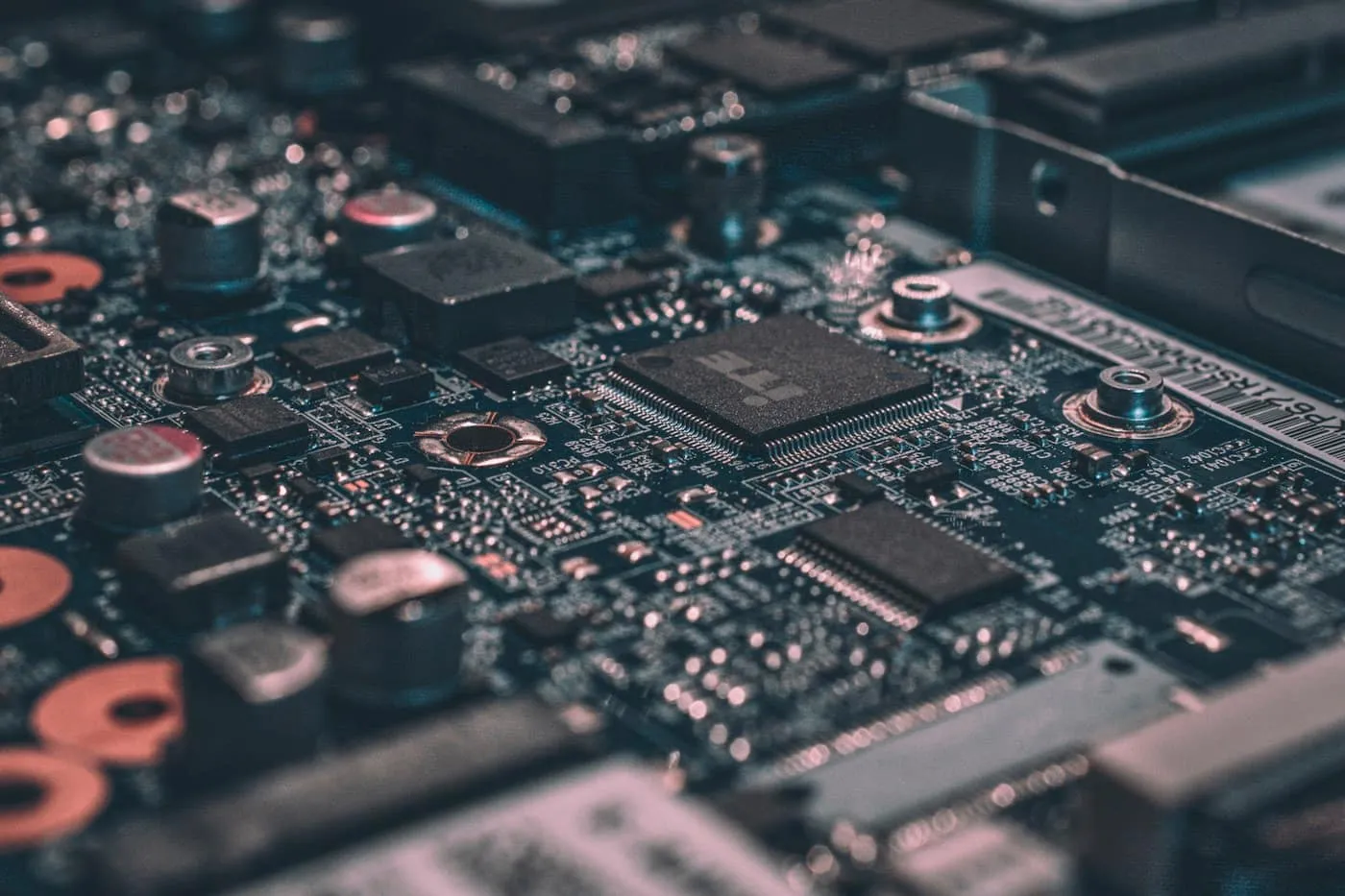 Macro shot of a dark circuit board with a central processor chip and capacitors