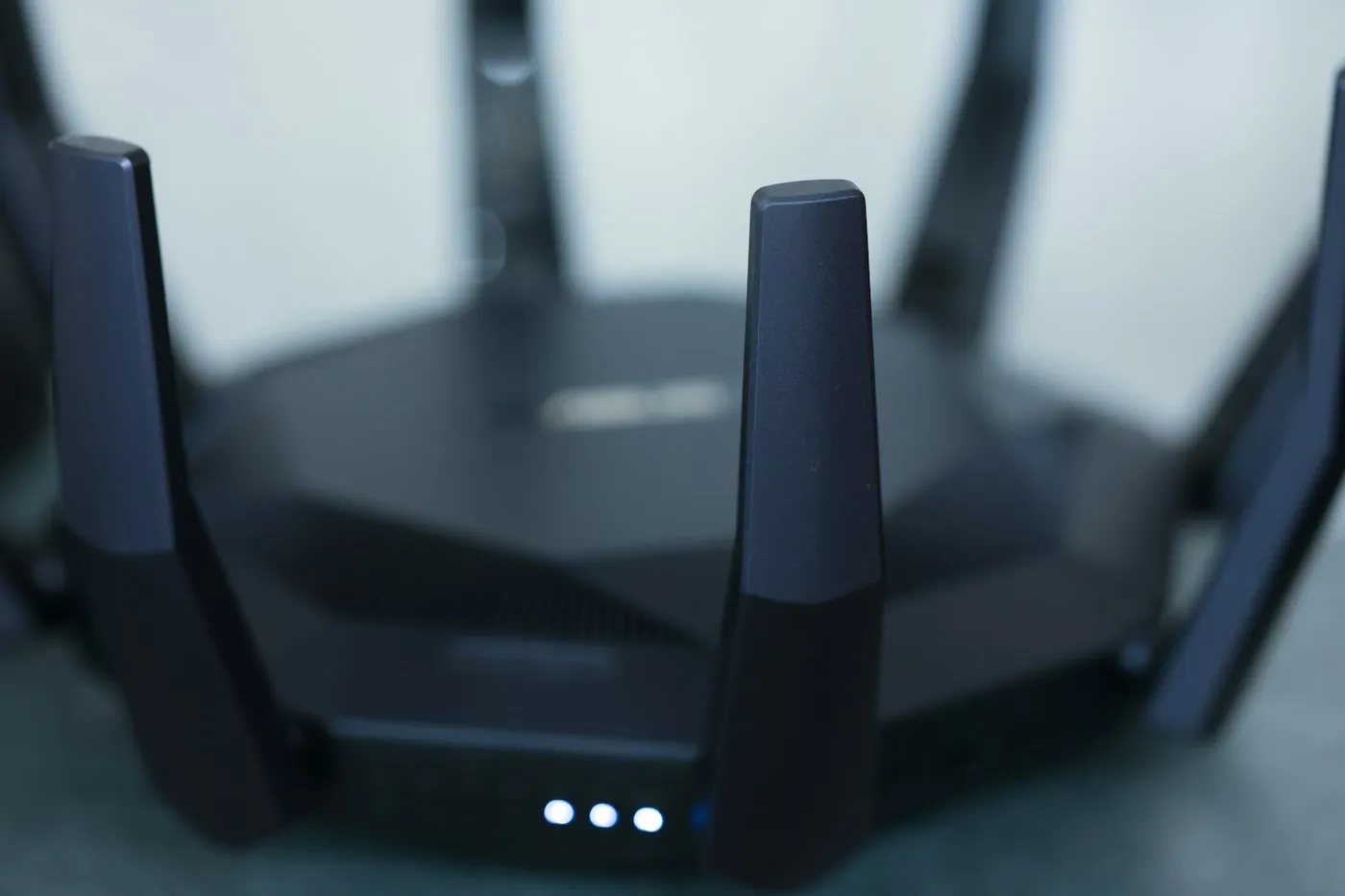 Black Wi-Fi router with tall antennas and three glowing white status lights