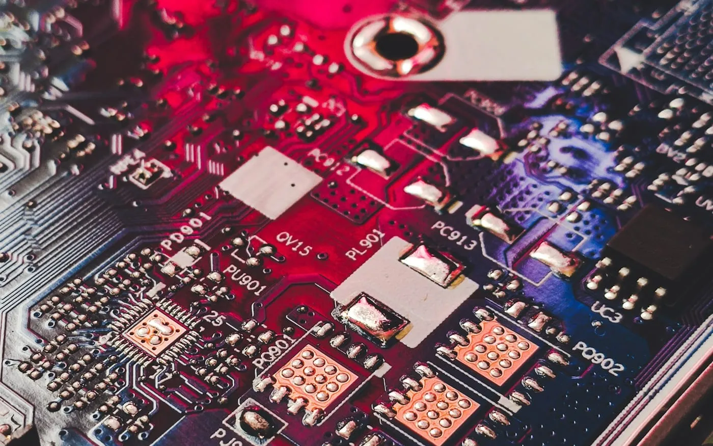 Macro close-up of a computer circuit board bathed in crimson and deep blue light