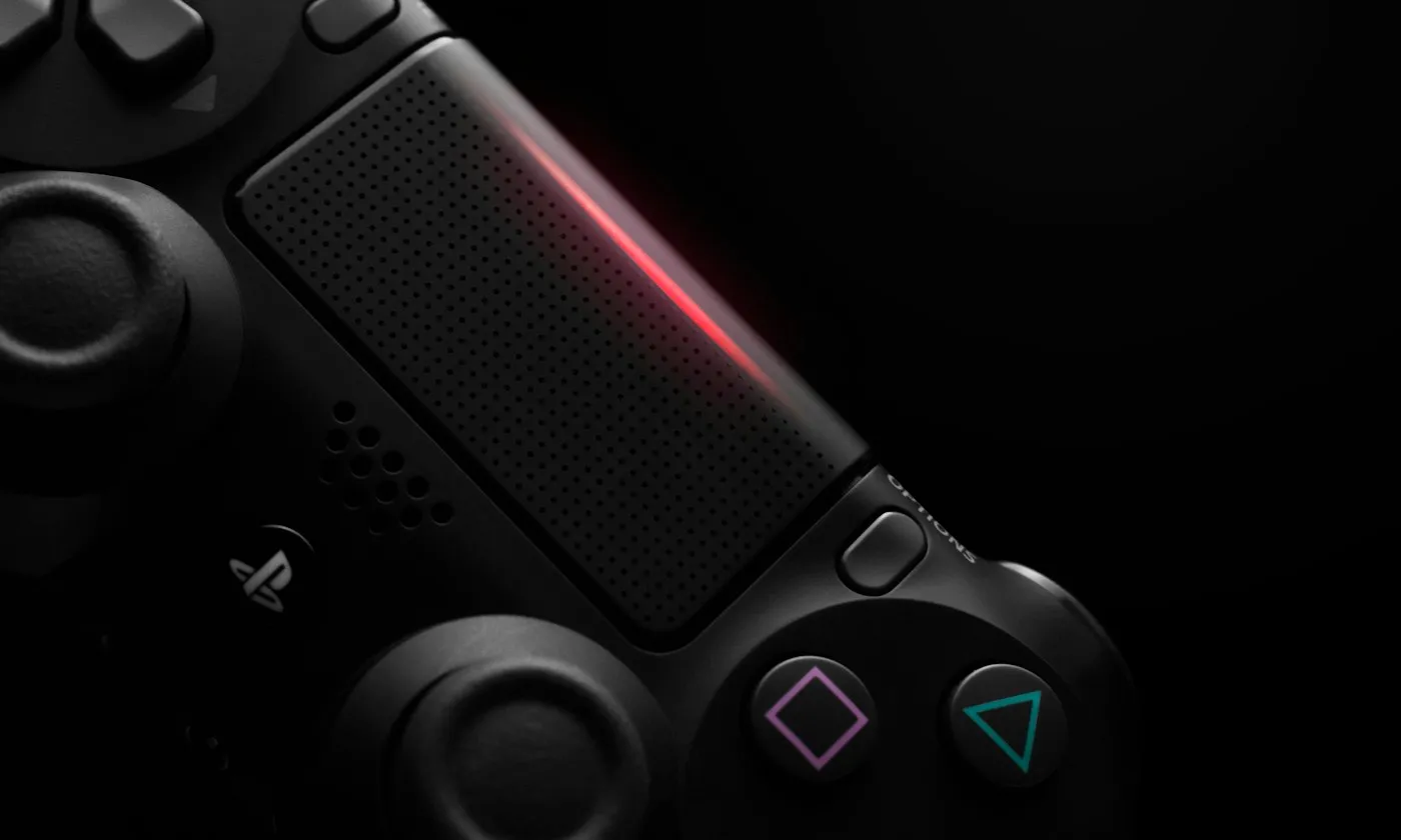 Close-up of a black game controller in darkness with a glowing red light bar